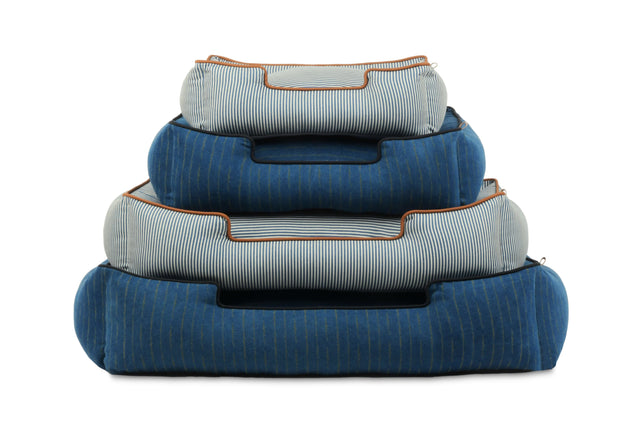 Stack of P.L.A.Y. Manhattan Lounge Beds in bolster style showcasing assorted sizes and blue tones for ultimate pet comfort.