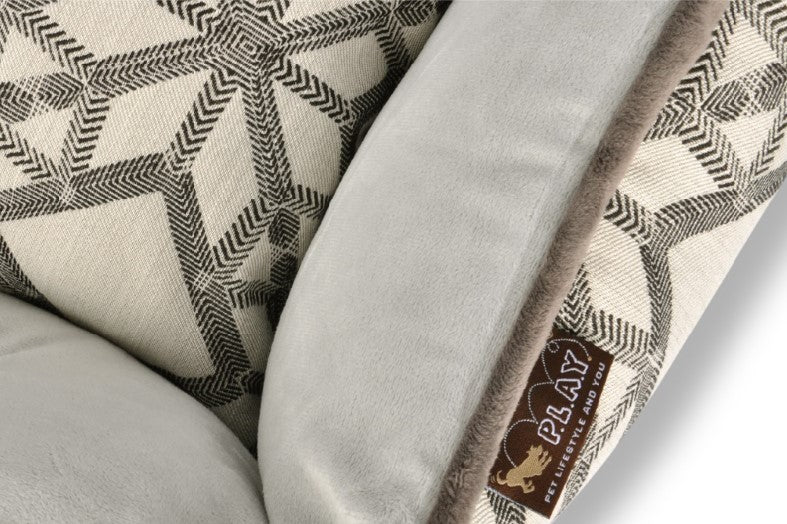 Close-up of P.L.A.Y. Solstice Lounge Bed showcasing its high supportive sides and striking geometric patterns in grey and beige.