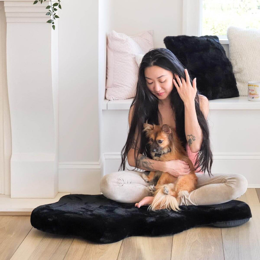 Woman and dog sitting on Hide shaped pet bed