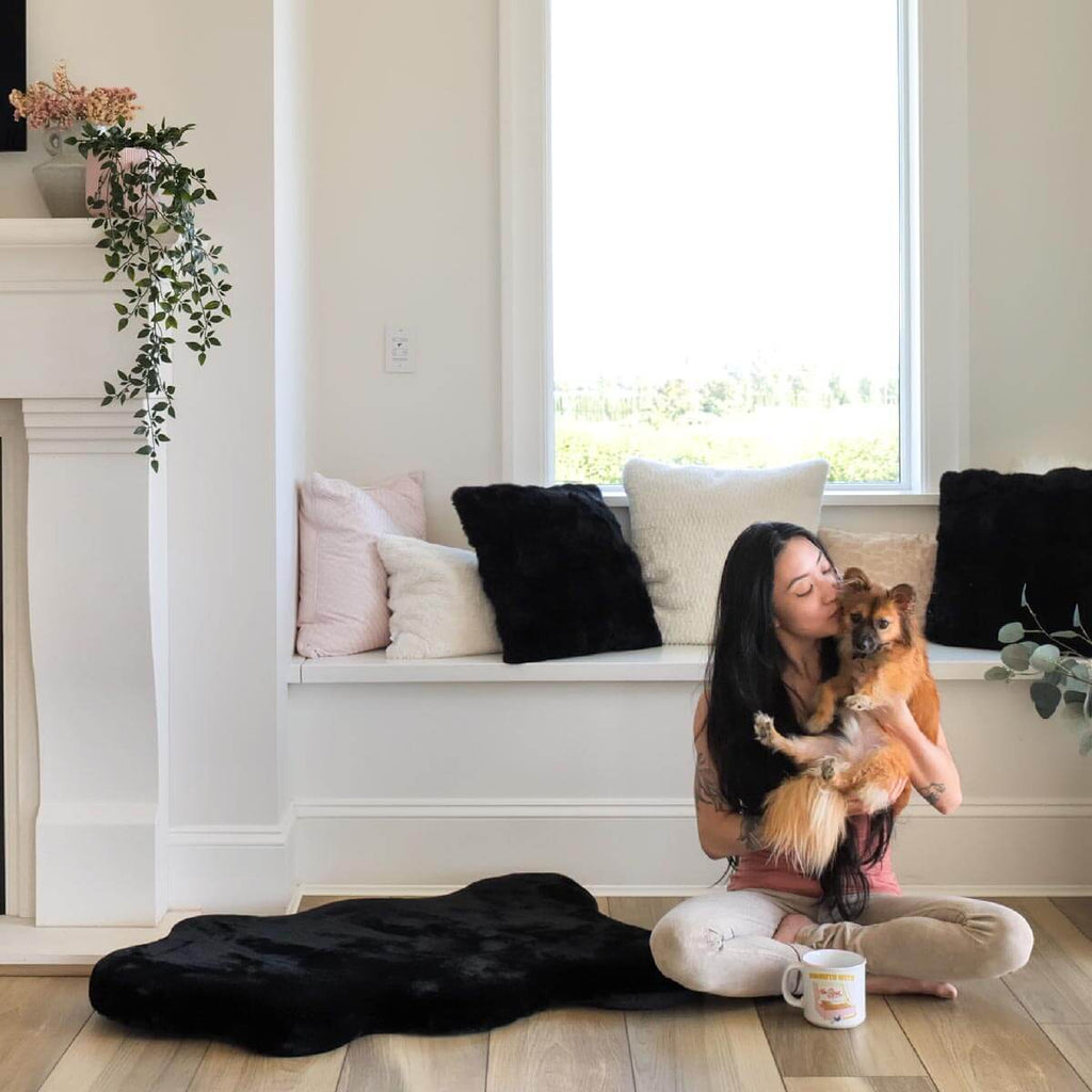 Woman and dog sitting next to Hide shaped pet bed 