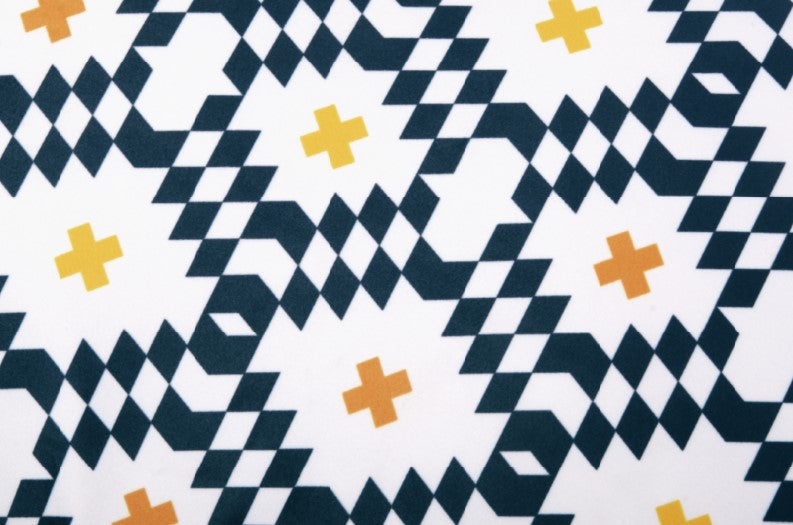 Geometric pattern fabric with black, yellow, and orange diamonds and crosses on a white background