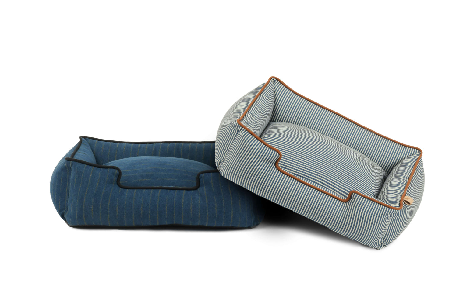 Two P.L.A.Y. Manhattan Lounge Beds in blue and striped patterns, bolster style dog beds with plush headrests, perfect for ultimate pet comfort.