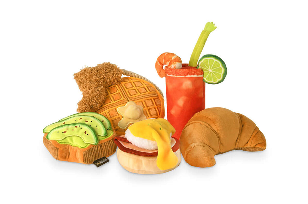 P.L.A.Y. Barking Brunch Toy Set featuring plush Eggs Benedict, avocado toast, croissant, waffle, and cocktail for dogs.