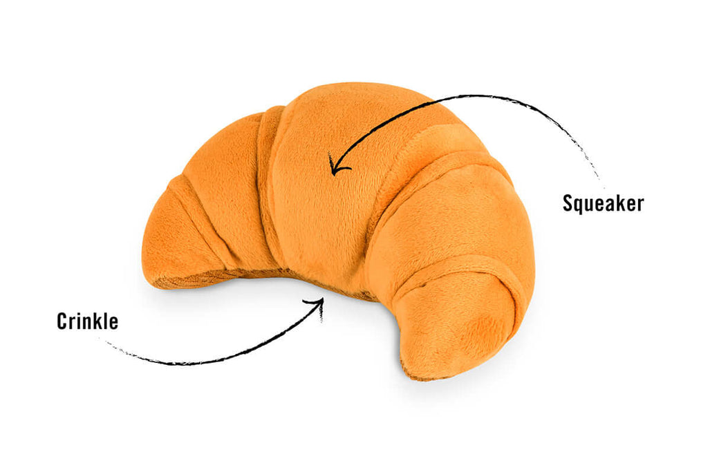 Croissant-shaped plush dog toy with crinkle and squeaker features from the P.L.A.Y. Barking Brunch Toy Set.