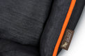 Close-up of P.L.A.Y. Denim Lounge Bed with orange piping and brand tag.