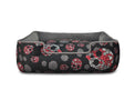 Skulls & Roses dog bed with raised sides and reversible cushion, featuring skull motif, roses, and baby's breath for stylish pet comfort.