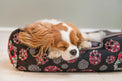 Dog sleeping on P.L.A.Y. Skulls & Roses Lounge Bed with skulls, roses, and baby’s breath motif providing comfort and style.