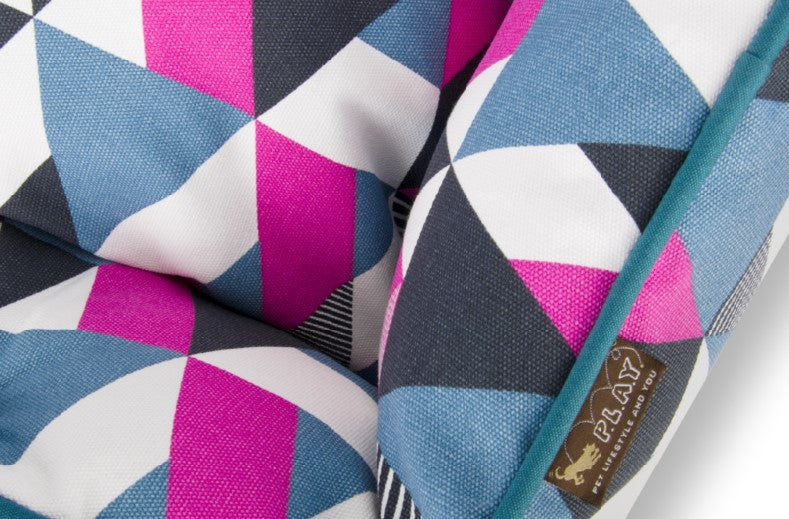 Close-up of colorful geometric pattern on P.L.A.Y. Mosaic Lounge Bed with bold pink, blue, and white shapes.